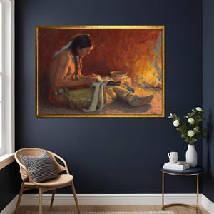 Puede incluir: Pintura enmarcada que representa una figura nativa americana sentada, concentrada en la artesanía. La obra de arte presenta tonos cálidos de naranja, amarillo y marrón, con un marco dorado. La escena incluye un fuego y cerámica, evocando la herencia cultural y el arte.