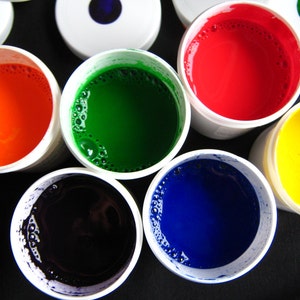 May include: Six small containers of paint, each with a different color: red, orange, yellow, green, blue, and black. The containers are white with a clear lid.