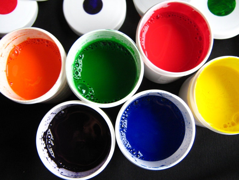 May include: Six small containers of paint, each with a different color: red, orange, yellow, green, blue, and black. The containers are white with a clear lid.