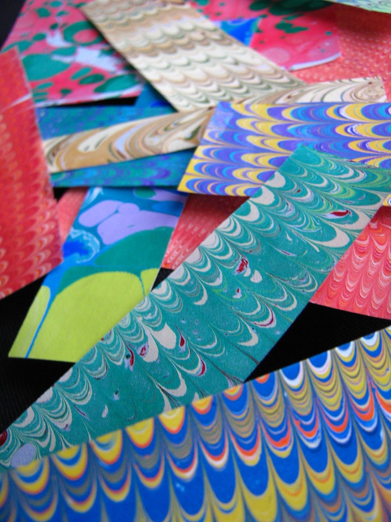 May include: A close-up of colorful marbled paper, with swirls of blue, green, red, yellow, and white. The paper is cut into strips and arranged in a layered pattern.