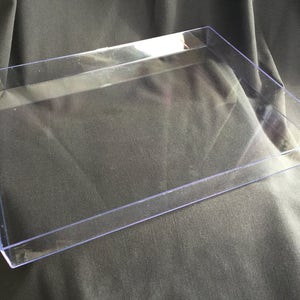 May include: A clear plastic tray with a rectangular shape. The tray is made of a durable, transparent material and has a smooth surface.
