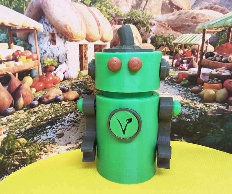 May include: A green robot toy with brown arms, eyes, and a hat. The robot has a circular emblem on its chest with a stylized arrow. The background features a whimsical village scene with food stalls and a small house.