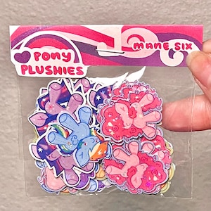 May include: A clear plastic bag filled with colorful pony plushie stickers. The bag's header reads "Pony Plushies" and "Mane Six" in pink and purple. The stickers feature various pony designs in shades of blue, pink, purple, and yellow.