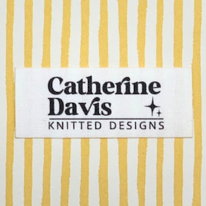 May include: A white rectangular label with the text "Catherine Davis KNITTED DESIGNS" in black. The label is set against a background of vertical yellow and white stripes.