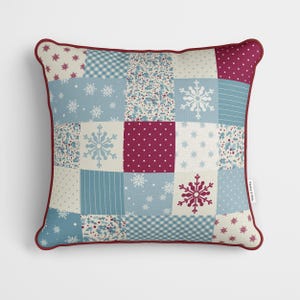 May include: A patchwork style cushion with a red, white and blue snowflake design. The cushion has a red border.