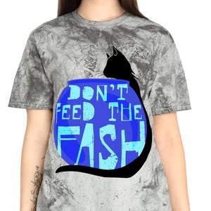 以下が含まれることがあります： 青い文字で「DON'T FEED THE FISH」と書かれた、黒い猫のシルエットが特徴のグレーのタイダイTシャツ。 デザインはシャツの前面の中央に配置されています。