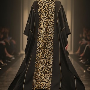 May include: A black and gold patterned kaftan with gold trim is worn by a person walking away from the camera. The kaftan has a gold, swirling design down the back. Gold high heels complete the look. The setting appears to be a fashion show.