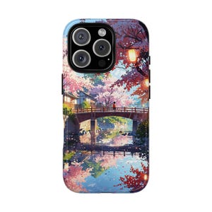 May include: A phone case with a colourful illustration of a Japanese scene. The image shows a bridge over a river, surrounded by cherry blossom trees. The case has a glossy finish and a blue border.
