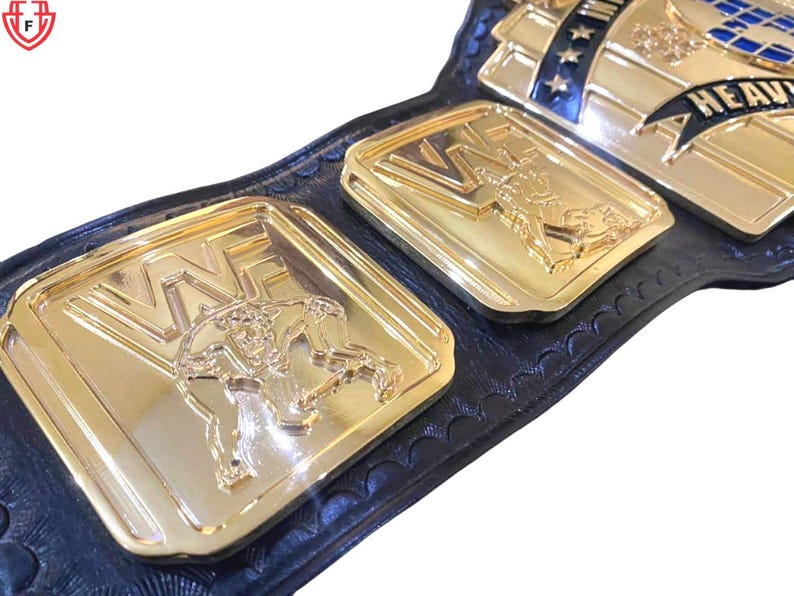 May include: Close-up of a gold and black wrestling championship belt. The belt features gold plates with the letters "WWE" and wrestler figures. The belt is made of black leather and has blue and white accents.
