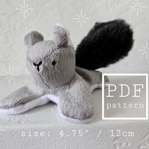 May include: A grey plush squirrel toy with a black fluffy tail and white accents. The toy is approximately 12 cm long. The image includes the text "PDF pattern".