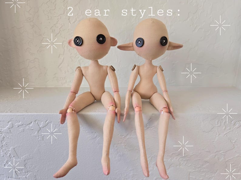 May include: Two handmade cloth dolls with button eyes and articulated limbs. The dolls are nude with two different ear styles, one with round ears and the other with pointed ears. The text "2 ear styles:" is above the dolls.