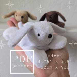 May include: Three plush bunny toys in white, tan, and brown are held in a hand. The white bunny is in the foreground. The image includes the text "PDF pattern" and size measurements of 4.75" x 3.5" (12cm x 9cm).
