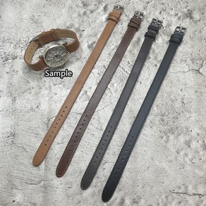 Puede incluir: Cuatro correas de reloj de cuero en marrón y negro. Las correas se muestran dispuestas sobre una superficie gris. El texto "Sample" es visible en la imagen.