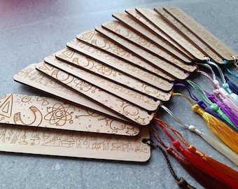 May include: A collection of wooden bookmarks with intricate laser-cut designs. Each bookmark features a unique pattern, including geometric shapes, scientific symbols, and stylized figures. Colorful tassels in various hues are attached to the bookmarks.