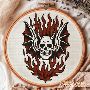 May include: A cross-stitch design featuring a skull with bat wings and flames in shades of black, white, and brown. The design is set in a wooden embroidery hoop. The word "Embrovia" is in the bottom right corner.