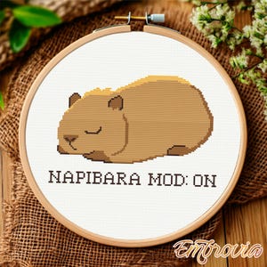 May include: Cross-stitch embroidery pattern featuring a sleeping capybara with the text "Napibara Mod: On".