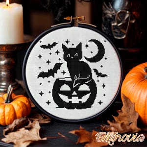 May include: A cross-stitch design in a round frame, featuring a black cat on a jack-o'-lantern, bats, stars, and a crescent moon. The word "Embrovia" is in the bottom right corner. Pumpkins and leaves surround the frame, creating a Halloween theme.
