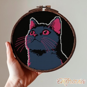 May include: A cross-stitch cat design in a wooden embroidery hoop. The cat is dark blue with pink ears, eyes, and whiskers. The background is black. The word "Embrovia" is in the bottom right corner.