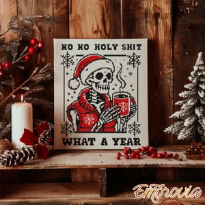 Puede incluir: Impresión en lienzo de un esqueleto pixelado con gorro de Papá Noel y chaqueta roja, sosteniendo una taza. El texto dice "HO HO HOLY SHIT WHAT A YEAR". La imagen está sobre un fondo de madera rústica con decoraciones navideñas.