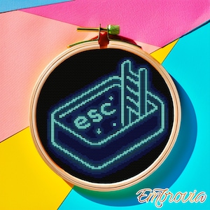 May include: A cross-stitch embroidery hoop with a neon blue pool design, including the word "esc" and a ladder. The design is set against a black background and framed by a wooden hoop. The background is a colorful mix of pink, blue, and yellow.