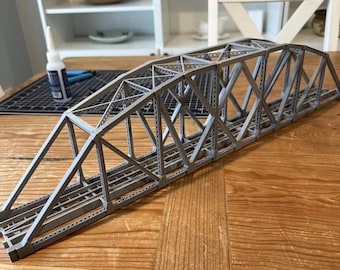Peut inclure: Un pont de chemin de fer miniature en métal gris avec une structure en treillis. Le pont est composé de nombreuses petites pièces et a un aspect réaliste.