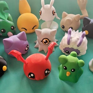 May include: A selection of brightly coloured 3D-printed figurines in diverse shapes. The figurines are predominantly in blue, green, yellow, purple, red, and white. The logo "SOUL MOON 3D DESIGN" is visible in the upper right corner.