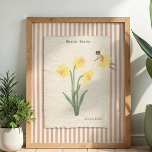 May include: A framed watercolour print depicting yellow daffodils with green stems and leaves. The artwork includes the text "March Fairy" and the date "14.03.2020". The frame is light wood with a striped background, suitable for home decor.