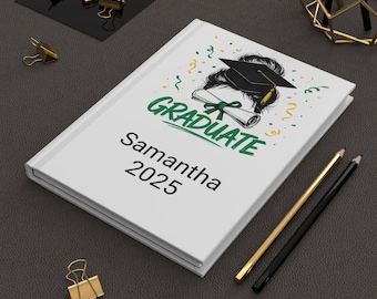 May include: White journal with the word "GRADUATE" in green and a graduation cap illustration. The name "Samantha" and the year "2025" are printed below. Gold and black pencils and gold binder clips are also visible.