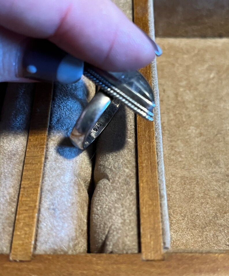 May include: A silver ring with a textured band and the inscription "925" on the inside.