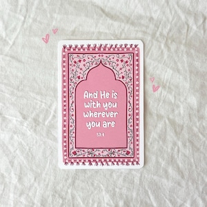 May include: A pink and white card with a floral design and the text "And He is with you wherever you are 57:4".