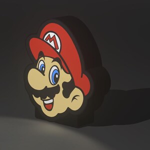 May include: A 3D-shaped light featuring the face of Mario from the Super Mario Bros. video game series. The light has a red hat with a white "M" on it, blue eyes, a black mustache, and a tan face. The light is black around the edges.
