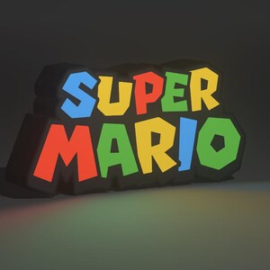 May include: A 3D-rendered sign featuring the words "SUPER MARIO" in bold, colorful letters. The letters are outlined in black and have a glowing effect, with red, blue, yellow, and green hues. The sign is likely a decorative item.
