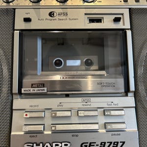 May include: Silver Sharp GF-9797 radio cassette recorder with a cassette tape inside. Features include balance, bass, treble, and record level controls. Includes APSS, Dolby System, and Soft-Touch Operation. Made in Japan.