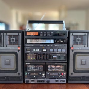 May include: A vintage Sony FH-55W stereo system featuring a central unit with a digital display showing 17:05, a radio tuner, graphic equaliser, and dual cassette decks, flanked by two detachable 3-way super wide speakers with grey mesh grilles.