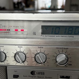 May include: Silver vintage stereo receiver with dials for volume, balance, bass, and treble. The digital display shows "101.80 MHz". Features include FM mode, stereo, and auto memory tuning.