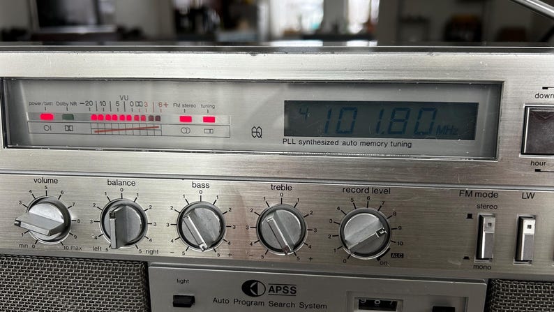 May include: Silver vintage stereo receiver with dials for volume, balance, bass, and treble. The digital display shows "101.80 MHz". Features include FM mode, stereo, and auto memory tuning.