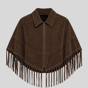 May include: A dark brown suede cape featuring a classic collar, a full-length front zipper closure, and a V-shaped seam across the chest. The hem is adorned with a row of metal eyelets and long, dangling suede fringe trim along the entire edge.