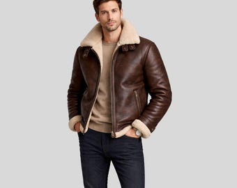 Puede incluir: Chaqueta de cuero marrón con cuello y forro de borrego color crema. La chaqueta tiene cremallera, dos bolsillos laterales y un estilo aviador clásico. El modelo lleva un jersey color beige y vaqueros azul oscuro.