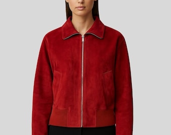 Puede incluir: Chaqueta bomber de ante roja con cremallera plateada. La chaqueta tiene cuello, bolsillos laterales y puños y dobladillo de canalé. Las mangas son largas y se combina con pantalones negros.