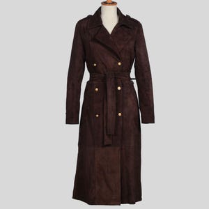 May include: A long brown suede trench coat with a double breasted closure, a belt, and gold buttons.