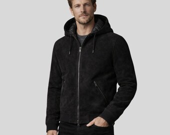 May include: Black hooded jacket with a zip-up front and two side pockets. The jacket has a textured appearance and a drawstring hood. The model is wearing a gray shirt and black jeans. The jacket is a versatile outerwear piece.