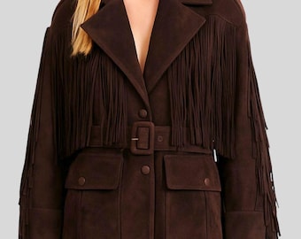 May include: Brown suede jacket with fringe detailing across the shoulders and sleeves. The jacket features a notched collar, a belted waist, and two front pockets. The jacket has a button closure and is a stylish outerwear piece.