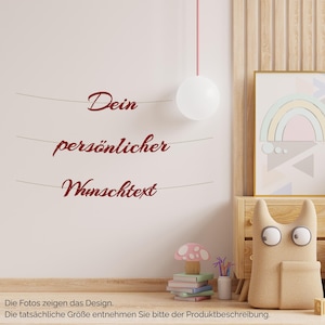 Könnte beinhalten: Ein Wandaufkleber mit drei horizontalen Linien, auf denen der dunkelrote kursive Text "Dein persönlicher Wunschtext" steht. Das Design wird auf einer hellen Wand präsentiert und zeigt den Schriftstil sowie das Layout für eine individuelle Wandgestaltung.