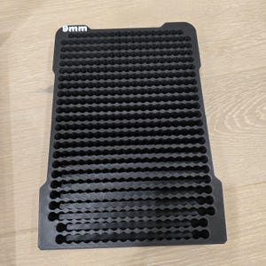 May include: Black rectangular tray with a grid of small, circular holes. The text "9mm" is printed in white at the top left corner. The tray is made of a matte black material.