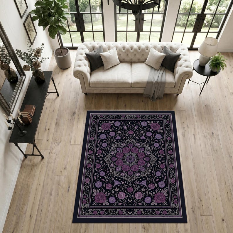 May include: A rectangular area rug featuring a dark black background with a central purple floral mandala pattern, surrounded by a decorative border of roses, vines, and small crescent moon symbols in shades of purple, lavender, and white.