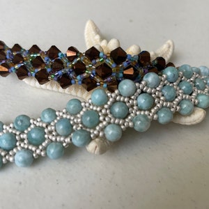 May include: Two beaded bracelets, one with brown and gold beads and the other with light blue and silver beads.