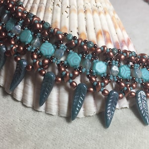 May include: A multi-strand necklace with copper, turquoise, and teal beads. The necklace features a fringe of teal leaf-shaped beads.