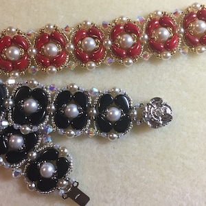 May include: Two beaded bracelets with pearl and crystal accents. One bracelet features red beads and the other features black beads.
