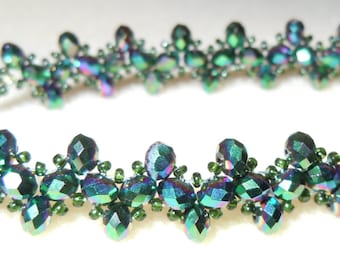 May include: A green and iridescent beaded bracelet with a silver clasp. The bracelet is made with small, faceted beads that are arranged in a repeating pattern.