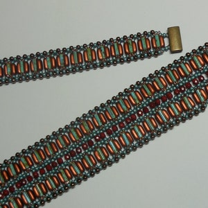 May include: A beaded bracelet with a geometric pattern in shades of brown, red, and teal. The bracelet has two metal clasps.